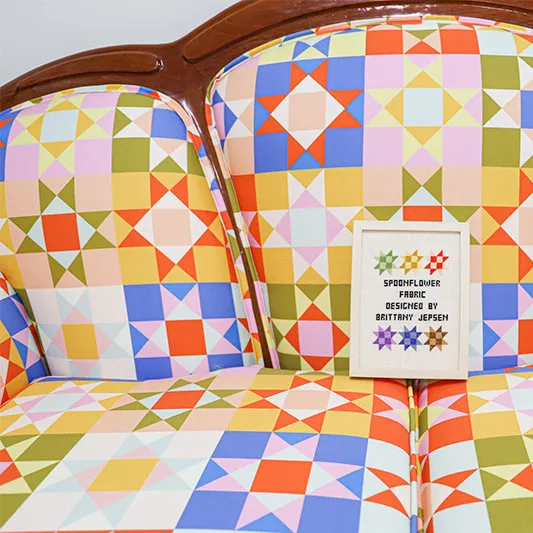 Settee reupholstered with a colorful and bright star quilt fabric.