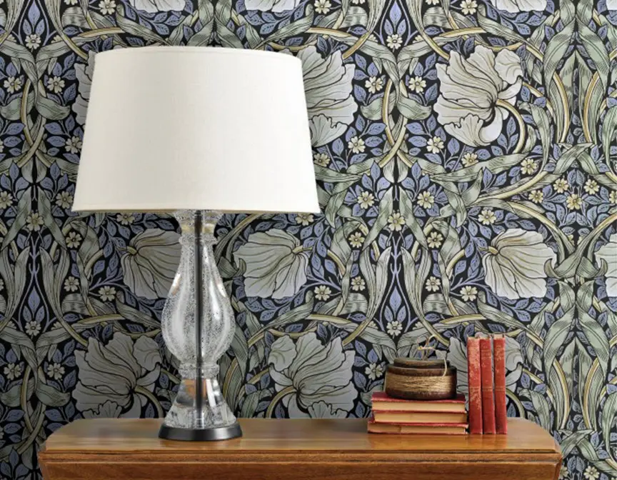 William Morris inspired Pimpernel wallpaper behind a table and lamp.